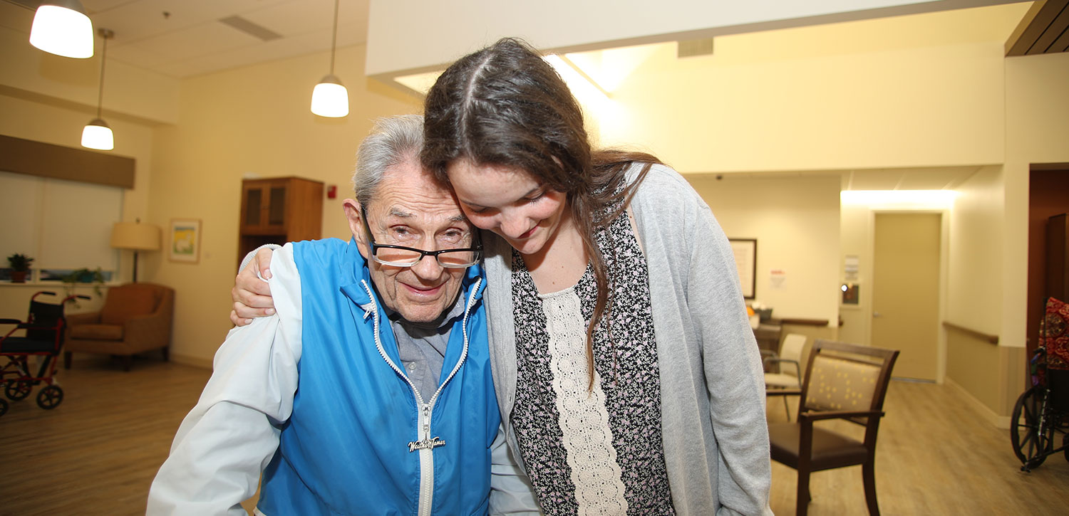 caregiver hugging senior man