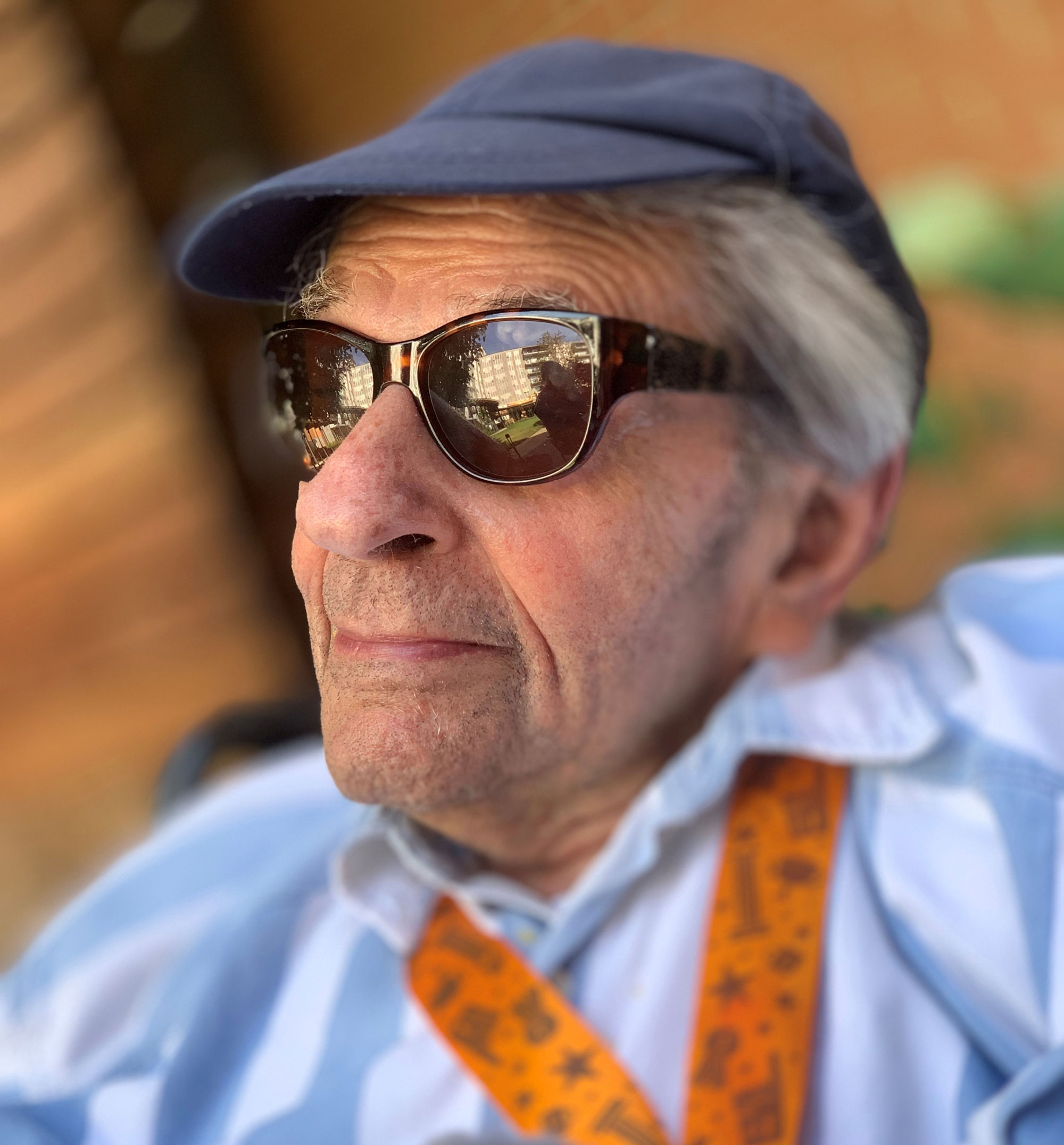A man wearing sunglasses, a blue hat and a blue shirt looking off into the distance.