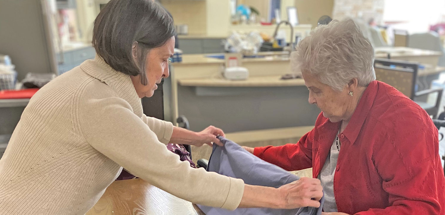 Two senior women folding a table cloth