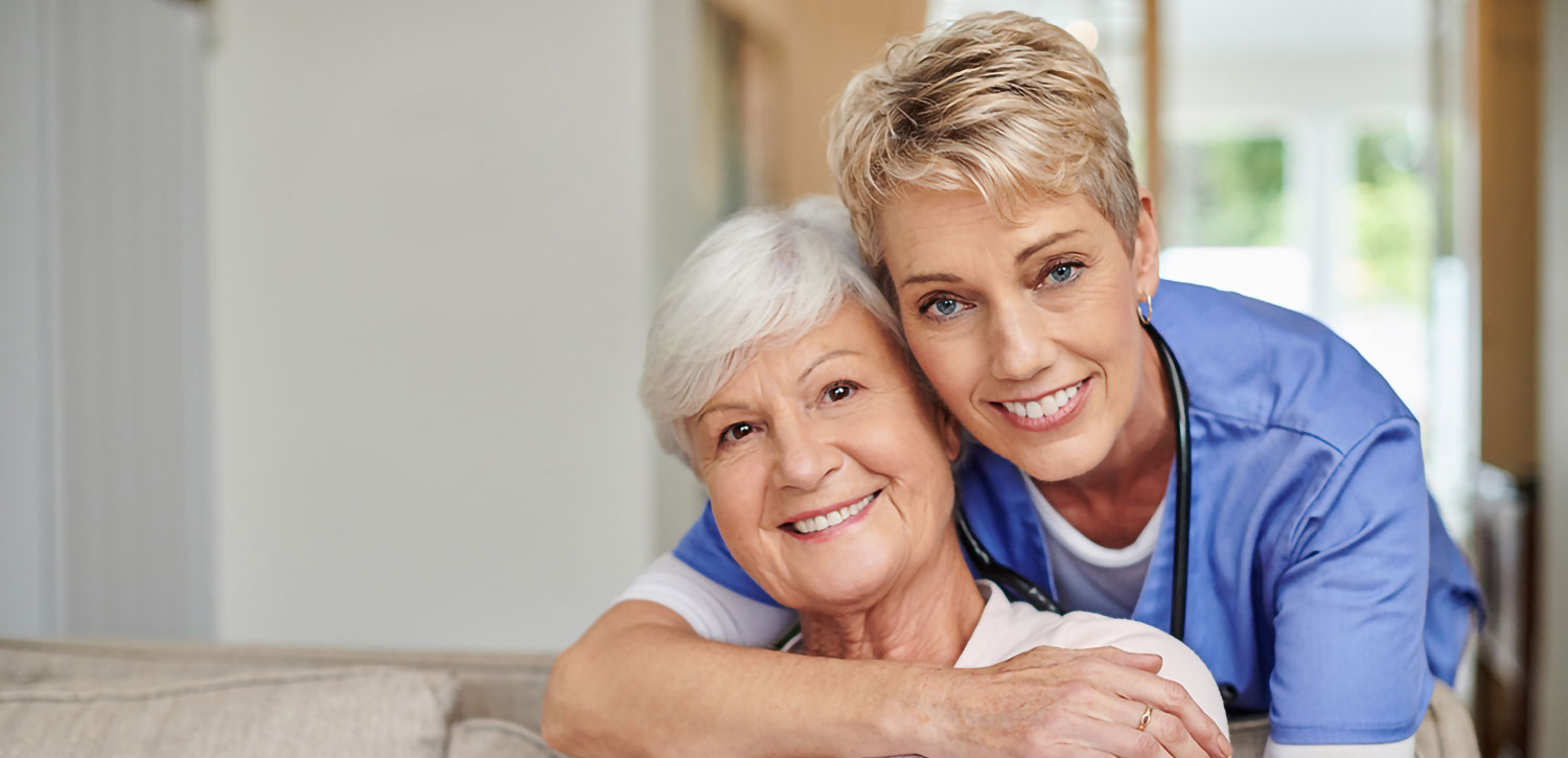 caregiver with her arm around a smiling senior woman