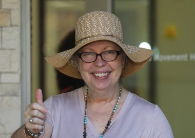 Woman in floppy hat giving thumbs up to camera