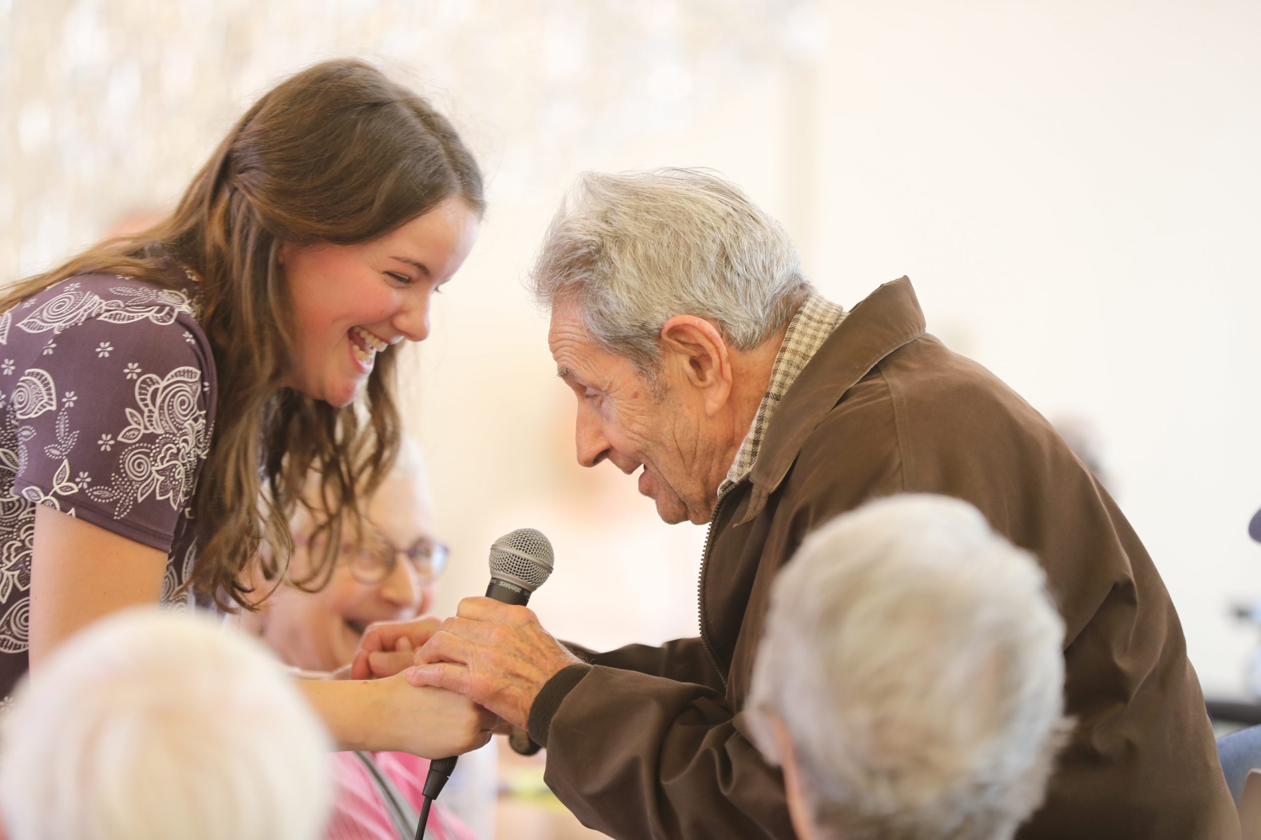 A40I9868 Senior Aged Male Abe's Garden Club Member clasping microphone with group leader