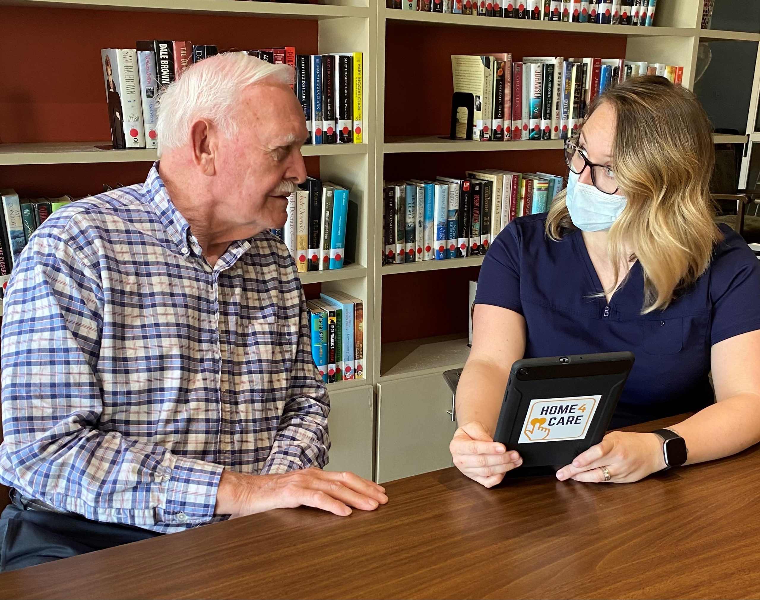 Abe_s Garden at Home At-home caregiver reviews a HOME 4 CARE®-enabled tablet with male dementia patient
