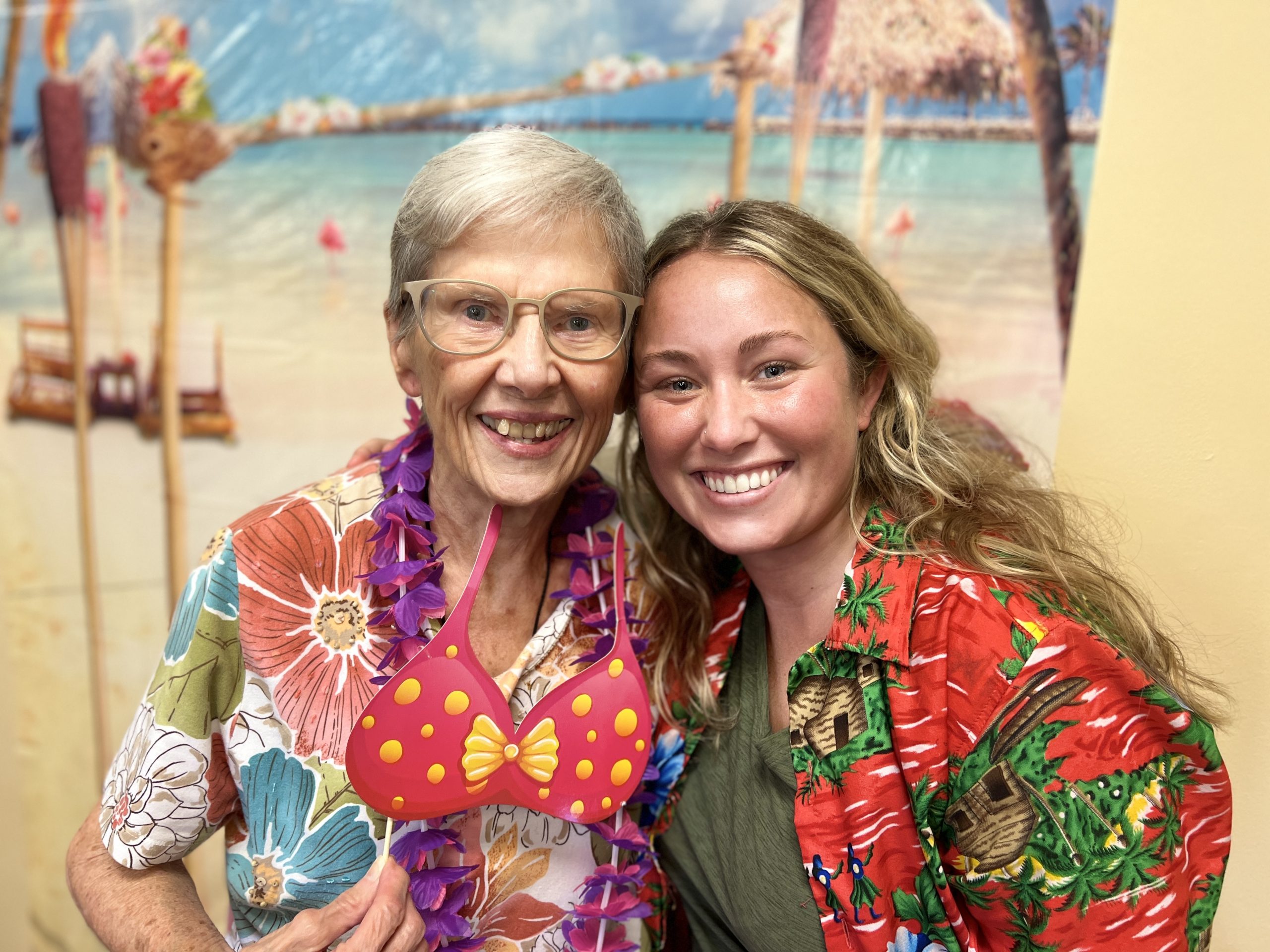 Independent Living resident and a staff member at Abe's Garden Community pose in Hawaiian shirts at a party