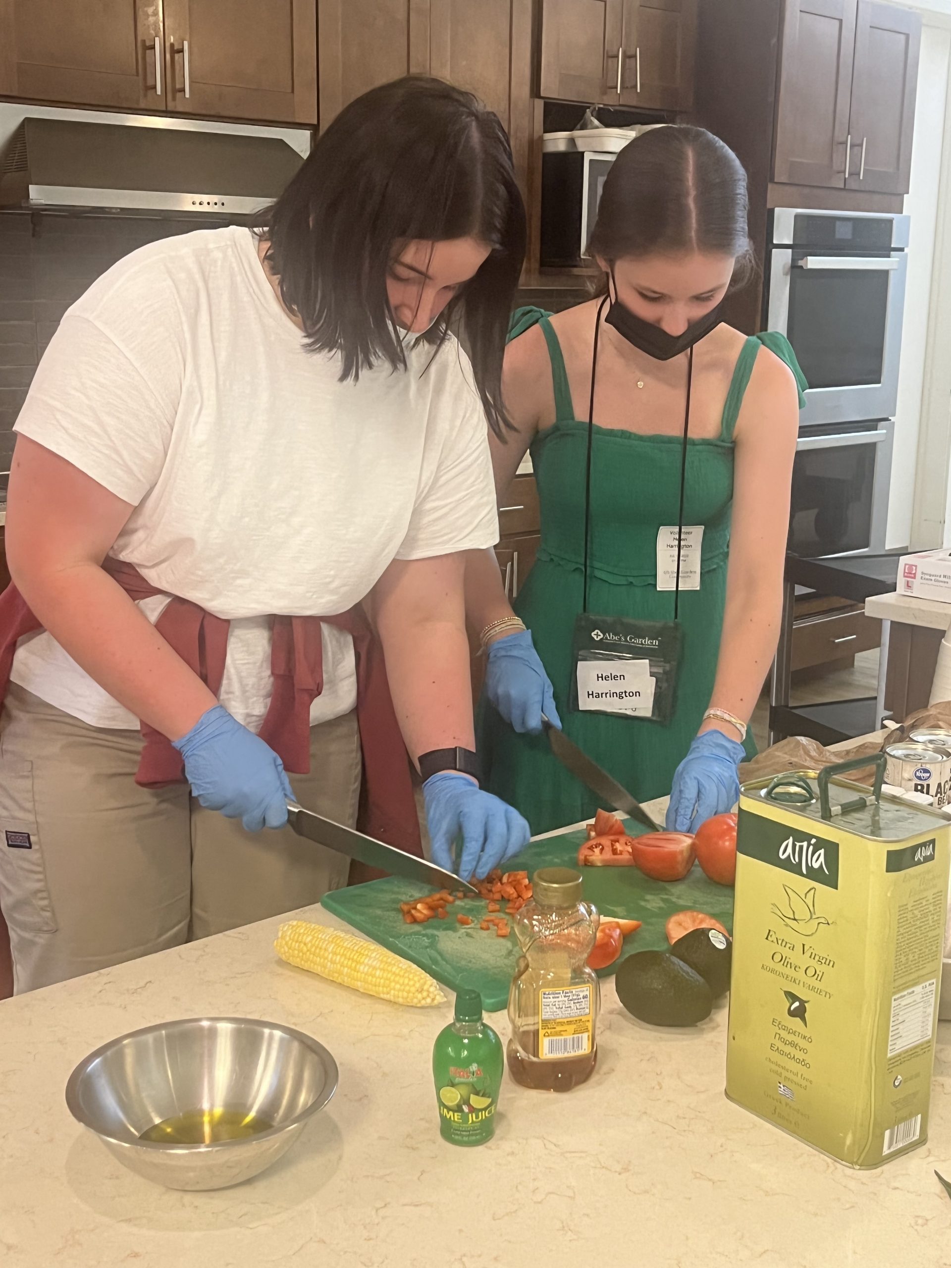 Two volunteers chop tomatoes for Abe's Garden Community culinary club