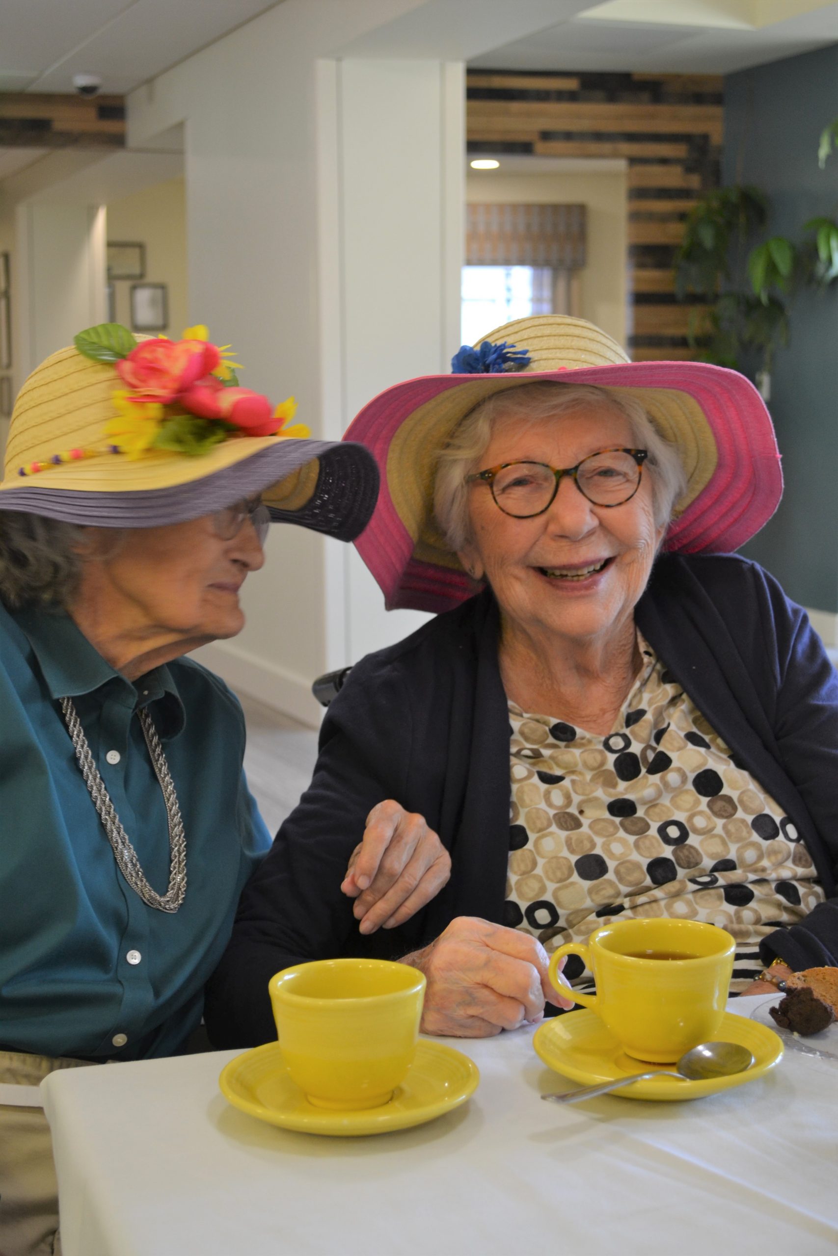 DSC_0906 Two Memory care residents in floppy hats enjoying tea and cookies in the dining room at Abe's Garden Community