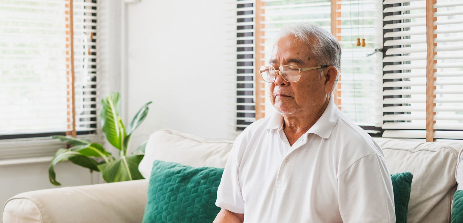 Senior man meditating on a sofa