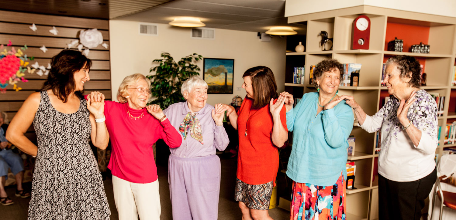 group of smiling seniors dancing in a conga line and laughing