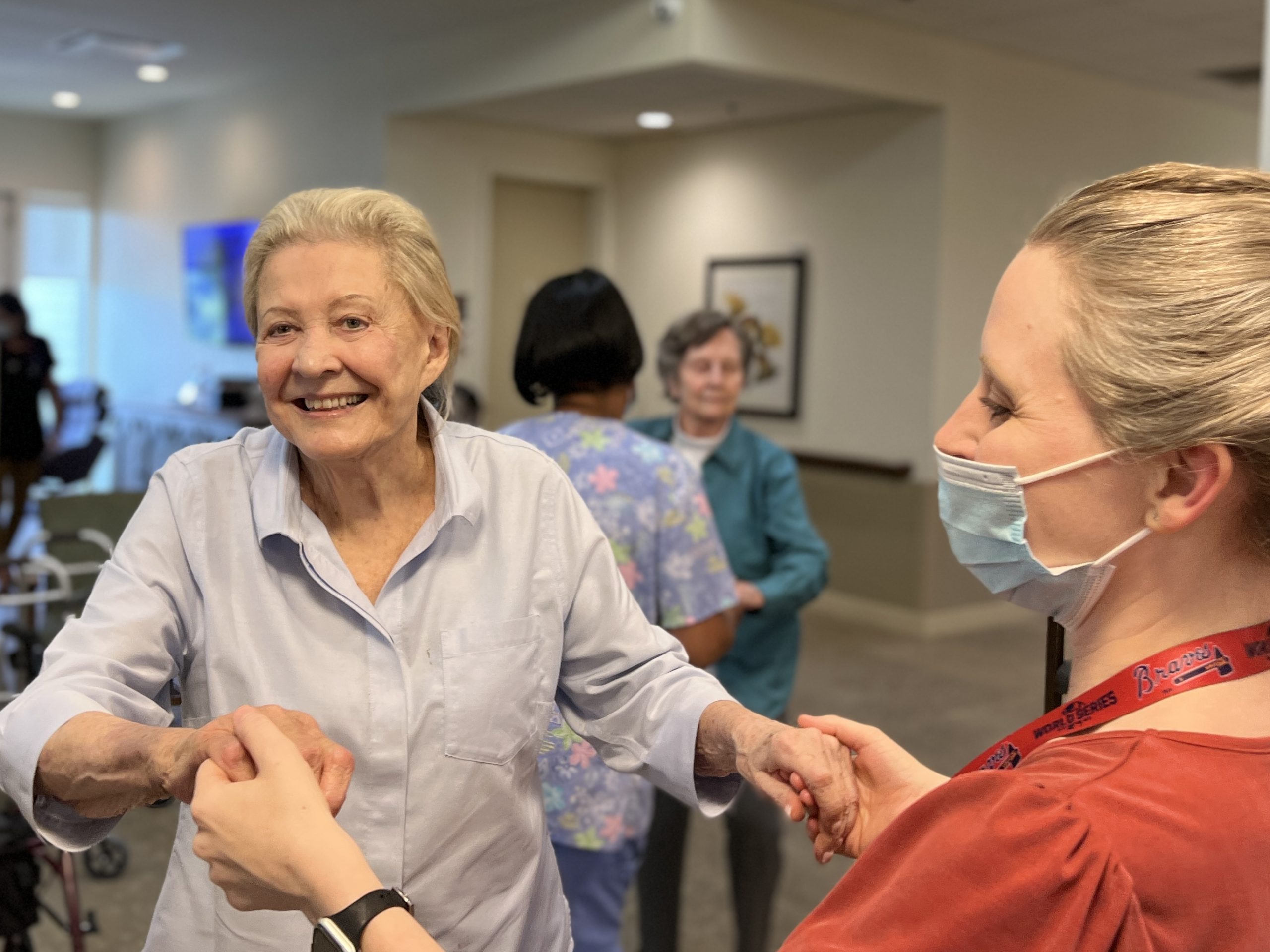 IMG_2006 A caregiver holds both hands of an elderly woman as she smiles