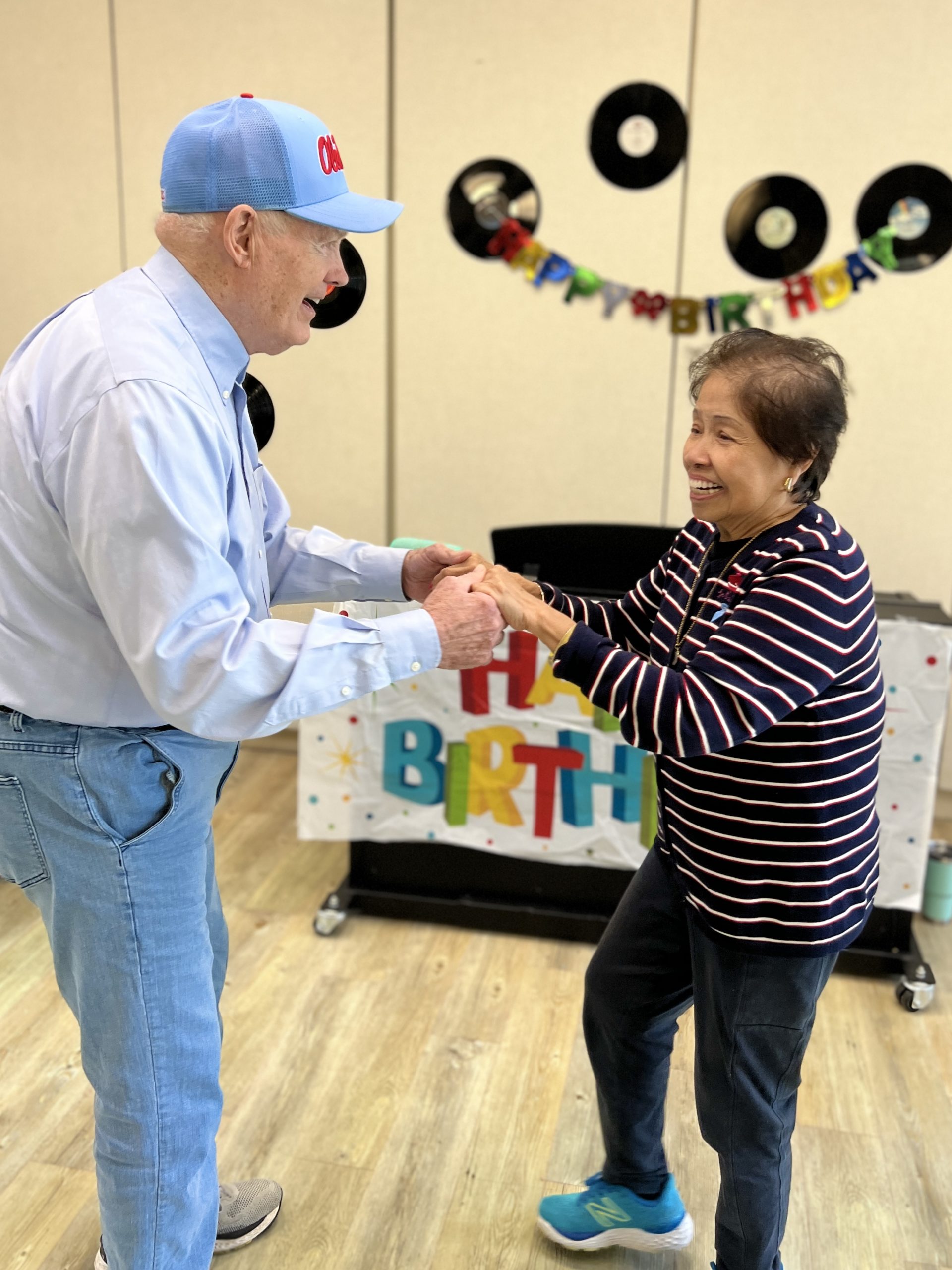 An elderly man and woman dance together at a birthday party hosted by Abe's Garden Community Group
