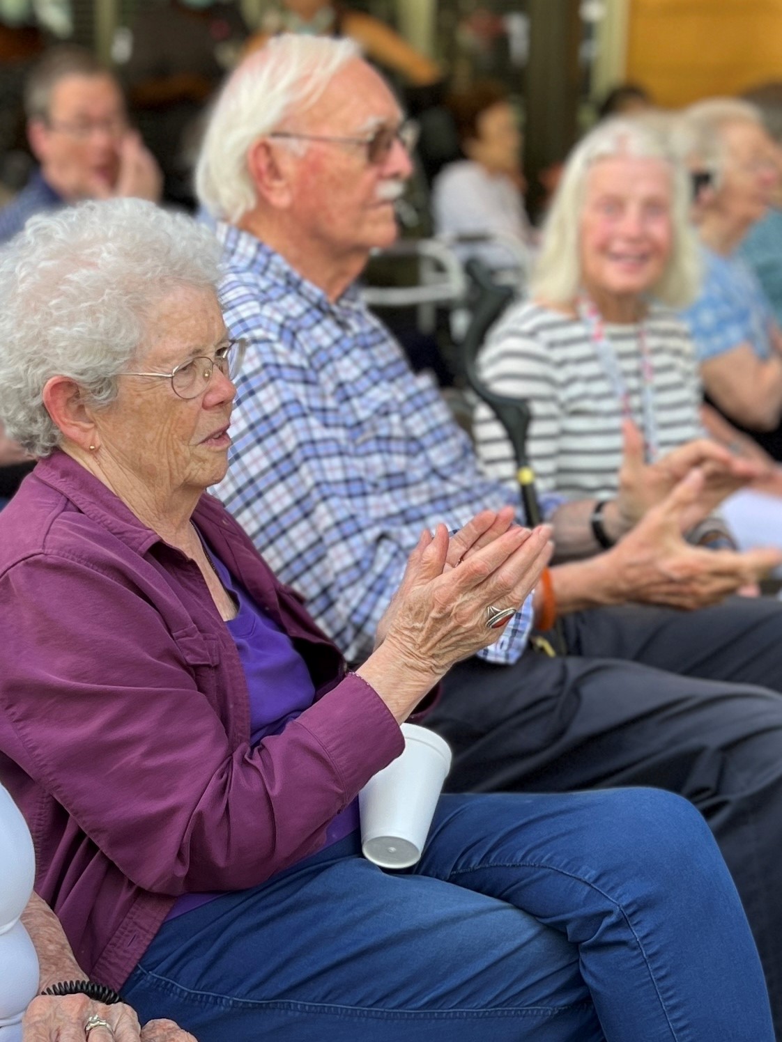 A group of three independent living residents sitting in a row applaud