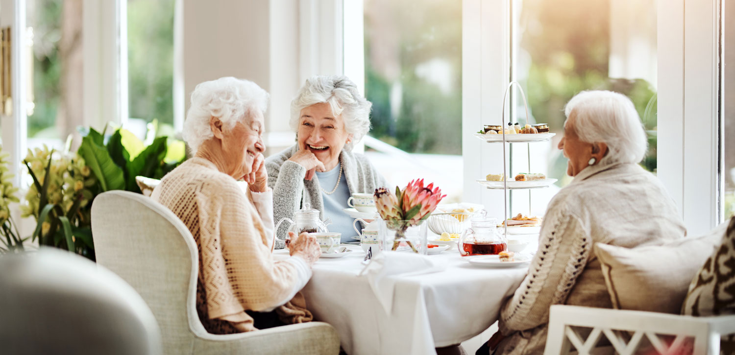 Group of senior friends laughing and enjoying tea together