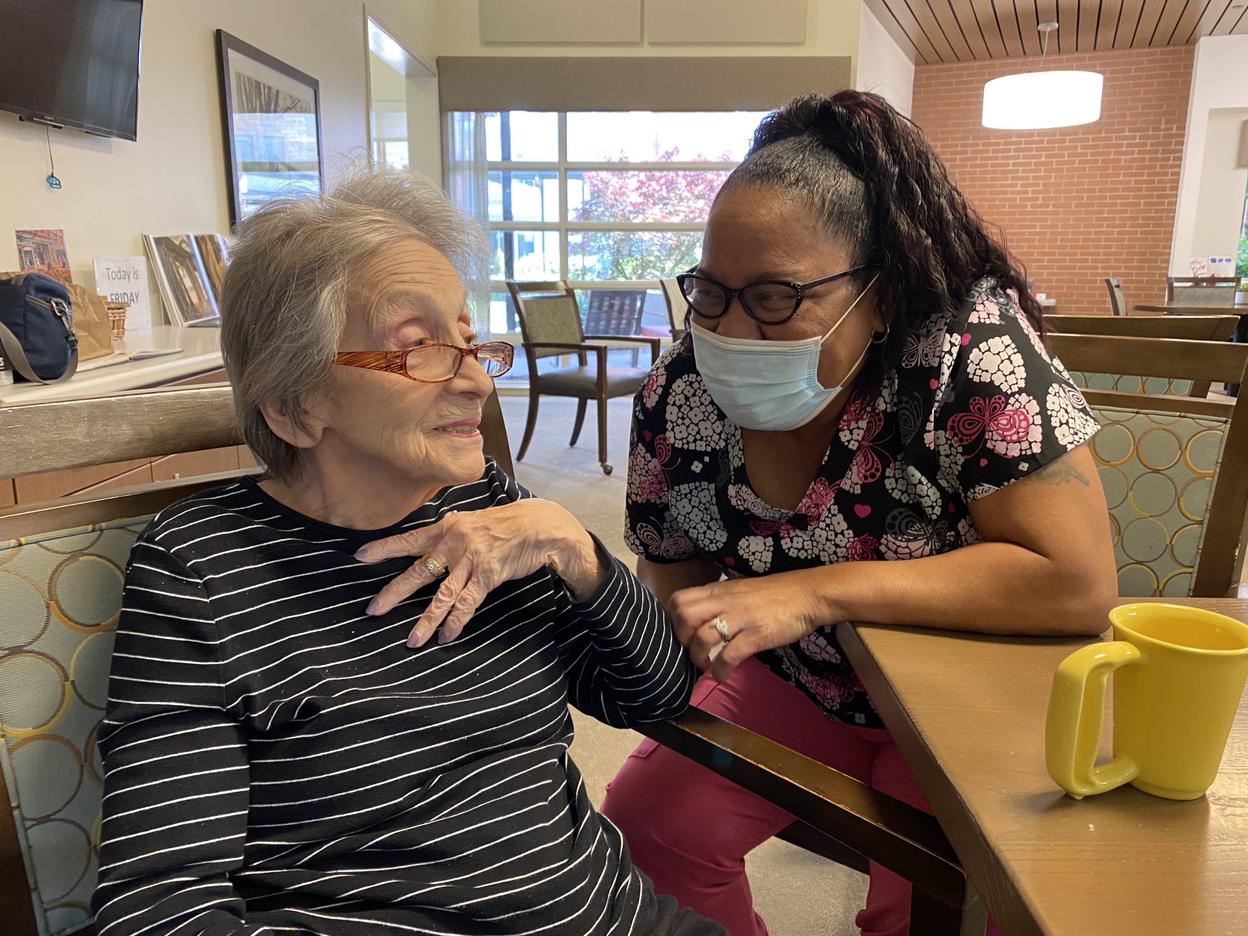 Caregiver chatting with Abe's Garden Community resident in dining room
