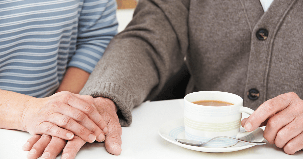 Two hands on a table with coffee comforting each other looking for the signs to move to senior living