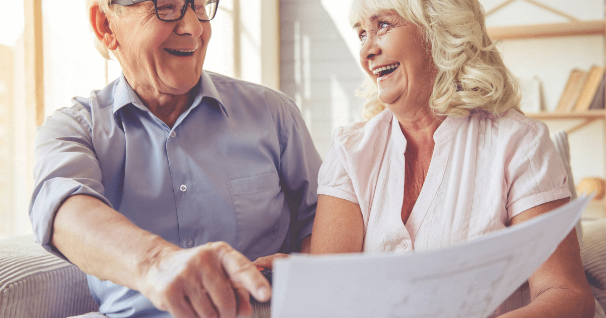 Senior couple in the process of a senior living search at a table reviewing paperwork.