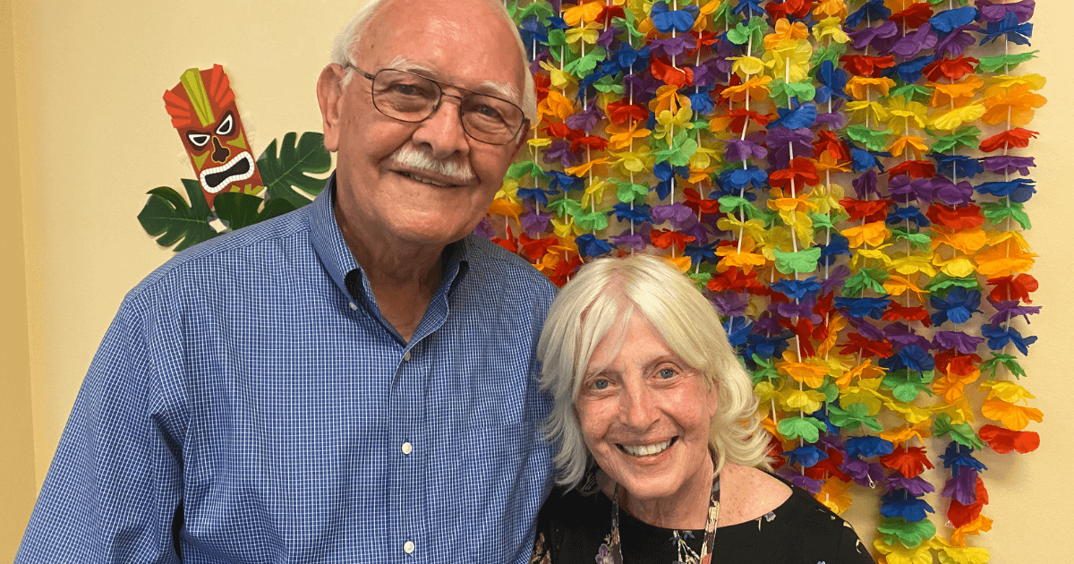 Elder couple with arms around each other looking at paying for senior living.