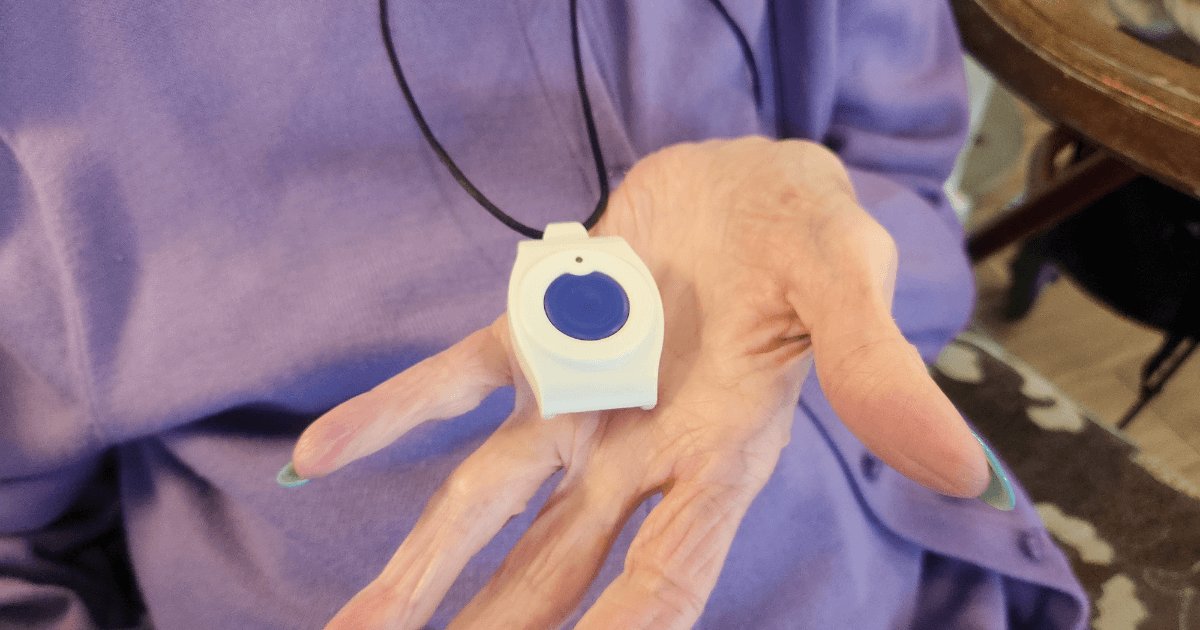 Woman's hand holding an alert necklace for safety and security.